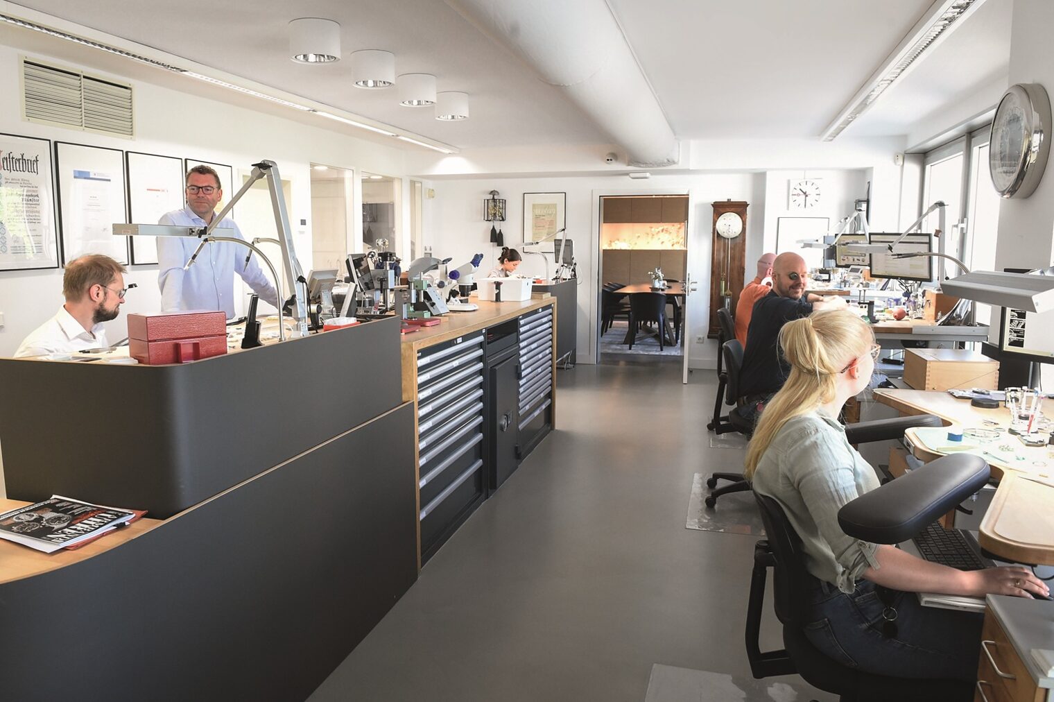 Die Uhrmacherwerkstatt der Firma Blome in Düsseldorf mit Mitarbeitenden an ihren Arbeitsplätzen
