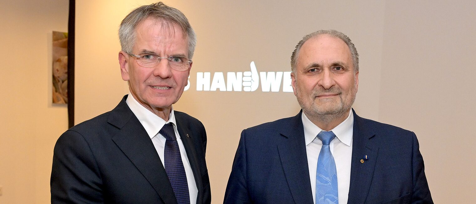 Andreas Ehlert und Hans Peter Wollseifer posieren für ein Pressefoto. Sie zeigen die Urkunde und die Goldene Medaille.