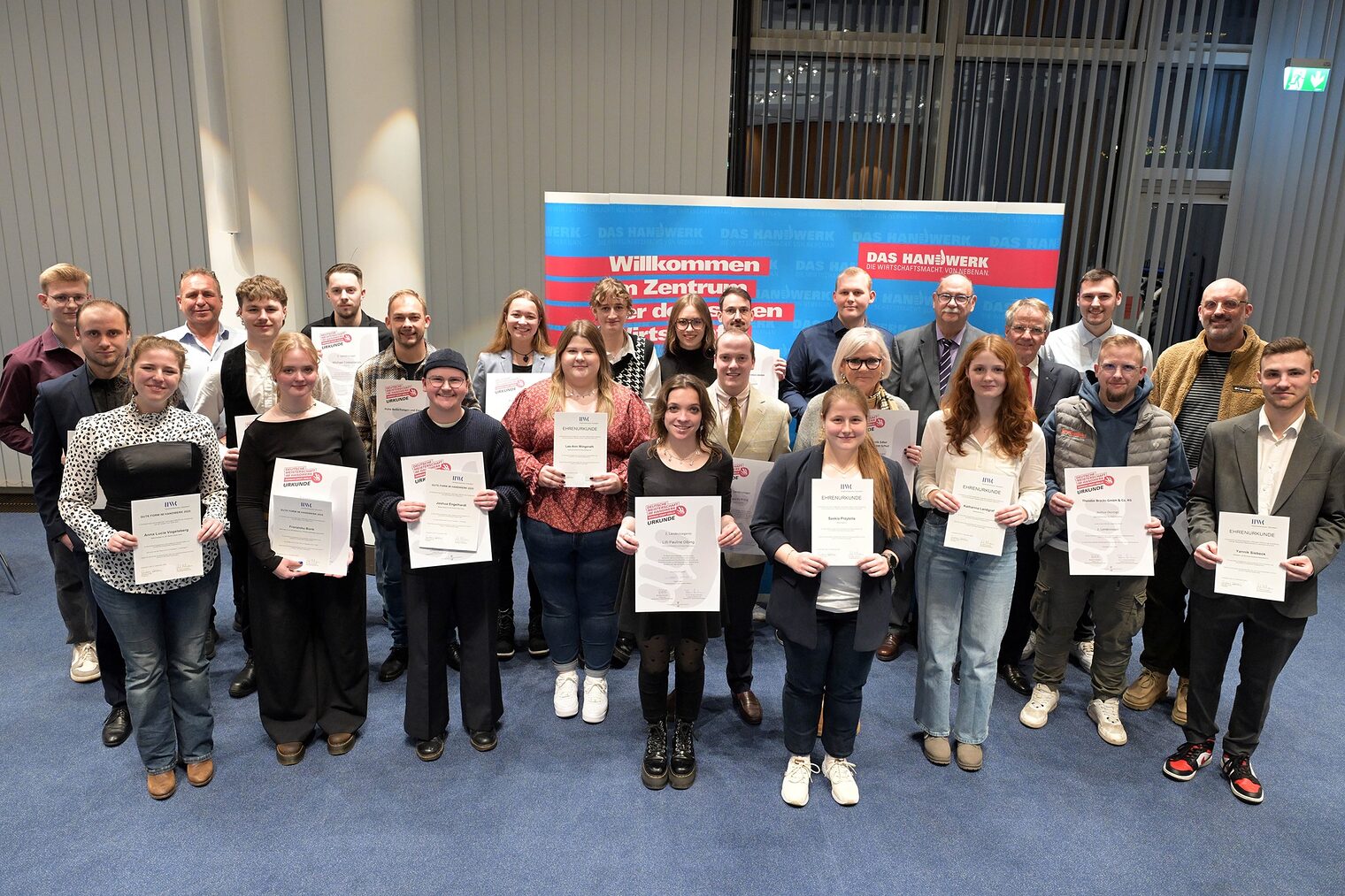 Die Teilnehmenden posieren für ein Pressefoto. Sie zeigen stolz ihre Urkunden.