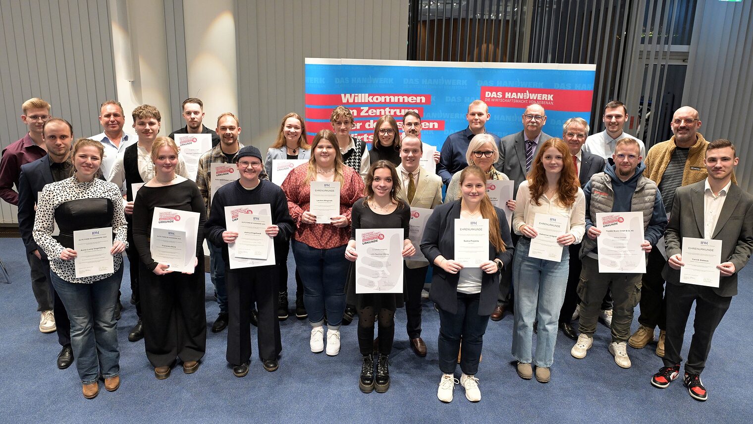 Die Teilnehmenden posieren für ein Pressefoto. Sie zeigen stolz ihre Urkunden.