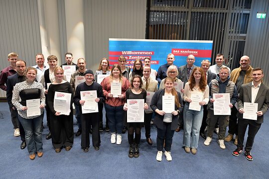 Die Teilnehmenden posieren für ein Pressefoto. Sie zeigen stolz ihre Urkunden.