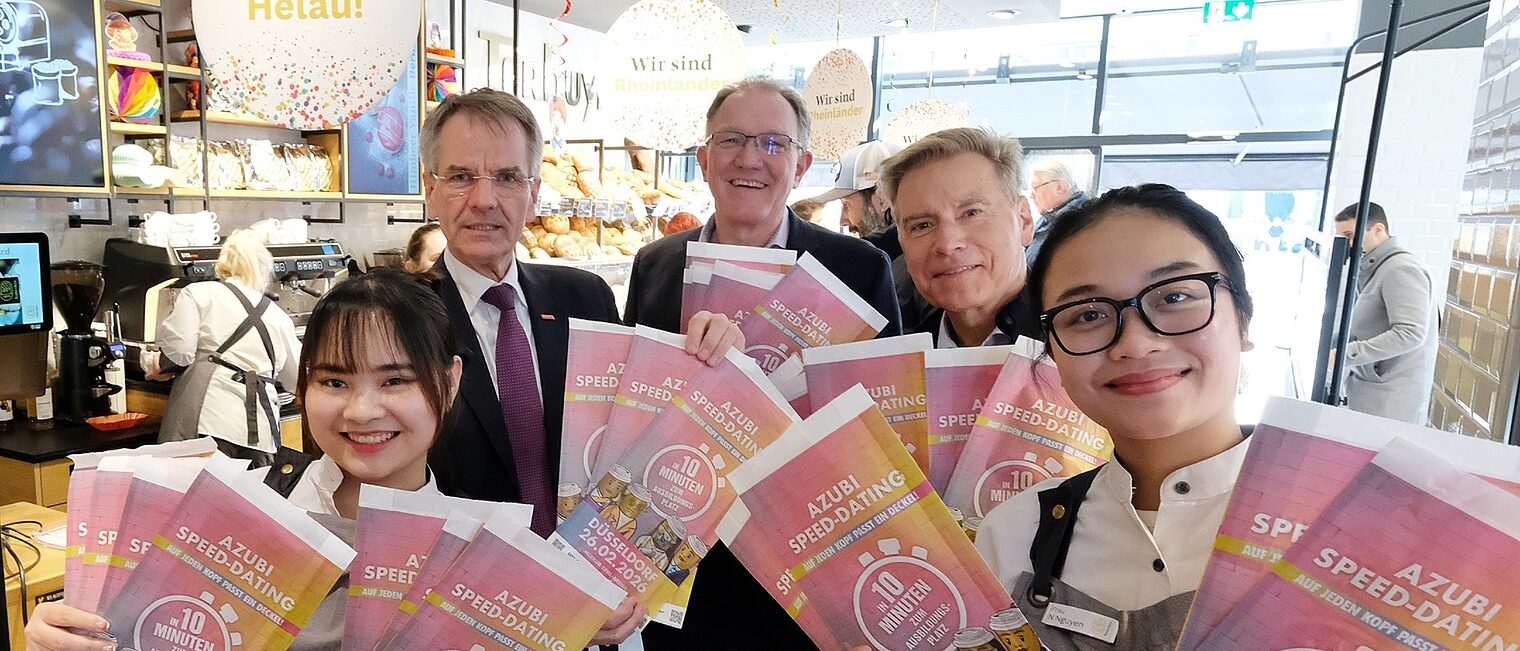 Die Akteure präsentieren stolz die bunt bedruckten Brötchentüten, die auf das Azubi-Speed-Dating hinweisen.