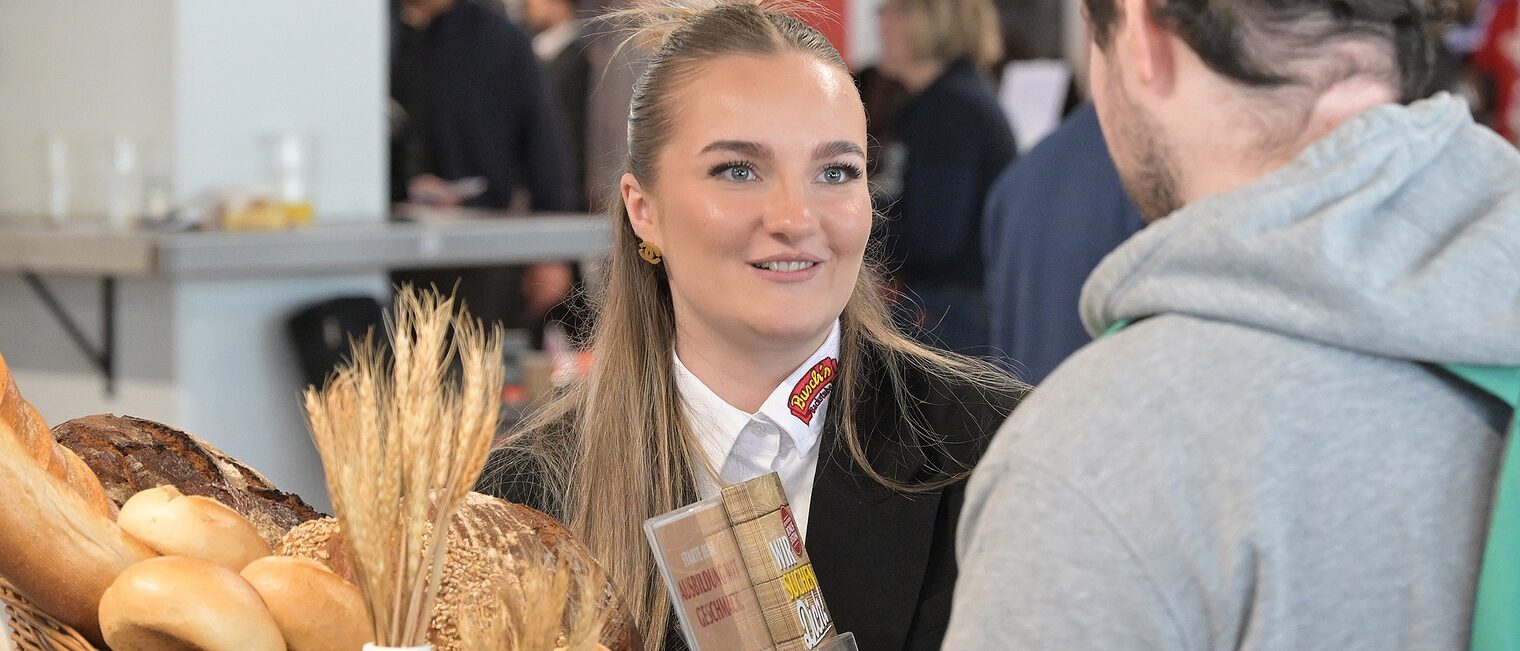 Eine Bäckerin berät einen ausbildungsplatzsuchenden Jugendlichen. Auf dem Beratungstisch steht ein Brotkorb.