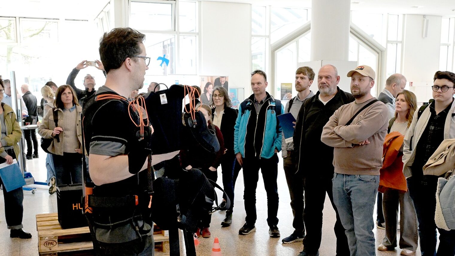 Ein Aussteller der Messe "Exoskelette und praktische Hilfsmittel für den Betriebsalltag" zeigt die Unterstützung beim Heben und Tragen von Lasten vor Publikum in der Handwerkskammer Düsseldorf.