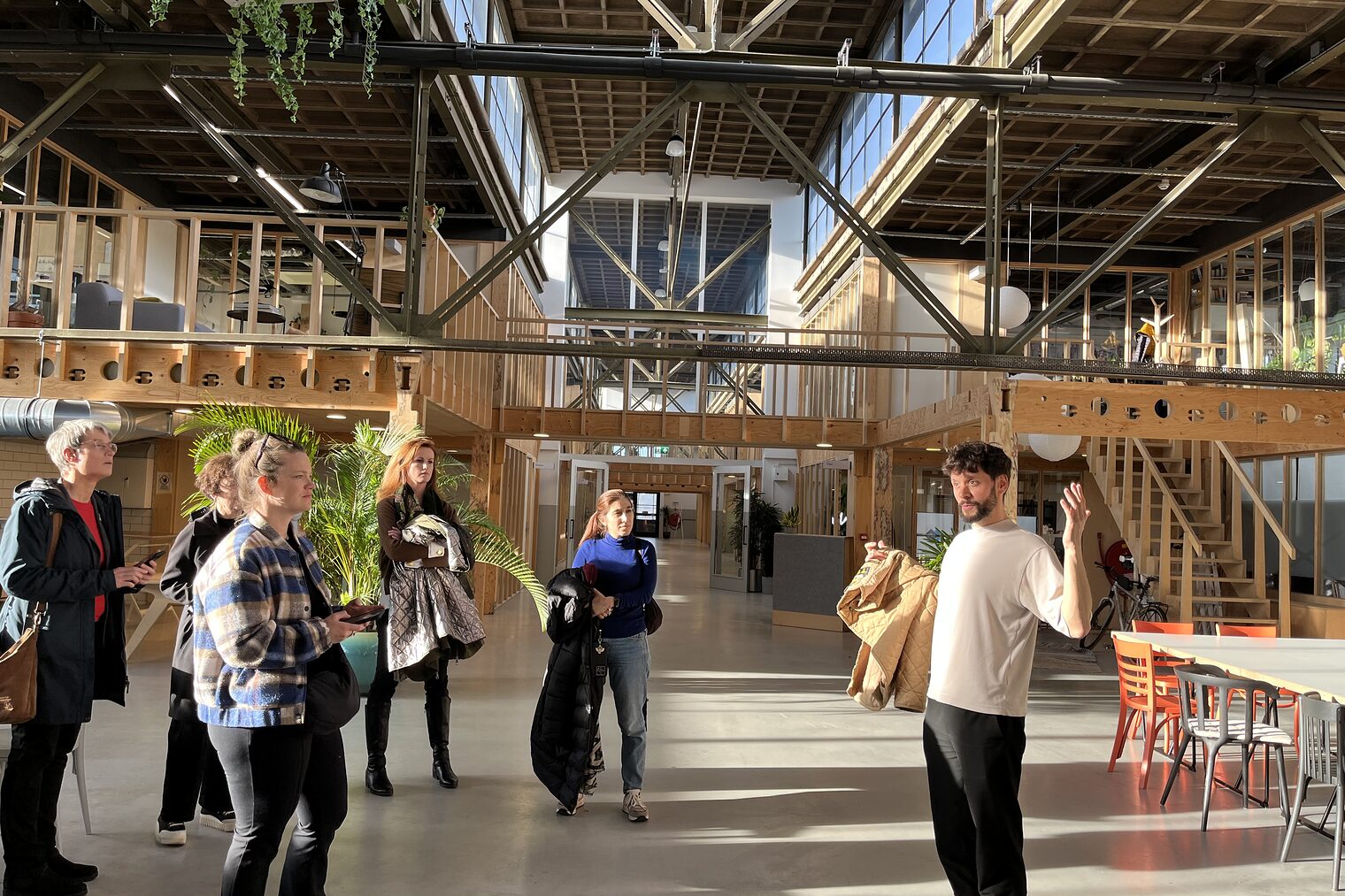 Gruppe junger Menschen steht in der Halle eines Holzbaus und lässt sich die Vorteile des nachhaltigen Bauens erklären. 