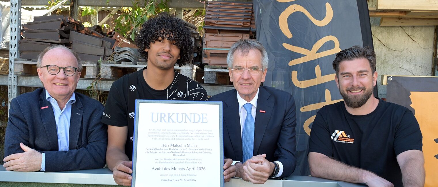 4 Personen posieren für ein Pressefoto. Der frisch ausgezeichnete Azubi des Monats zeigt seine Urkunde.