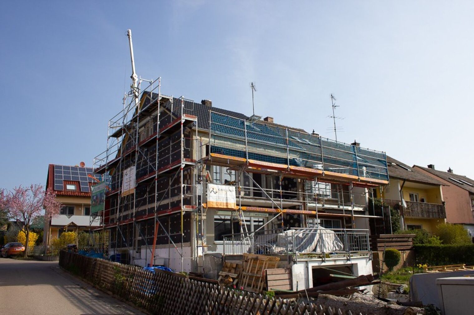 Auf dem Bild ist ein Haus von außen zu sehen, welches gerade modernisiert wird. Das Haus ist von einem Baugerüst umgeben.