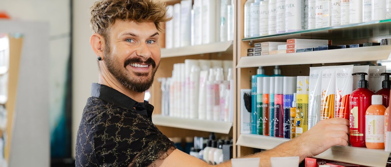 Friseur Jens Legeland vor einem Regal mit Haarpflegeprodukten