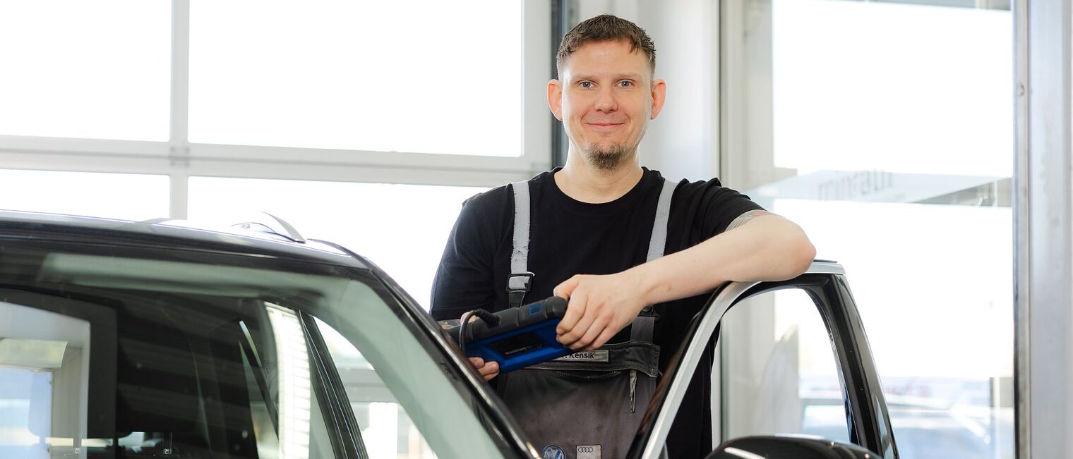 Thomas Kensik lehnt in der Werkstatt an einer geöffneten Autotür.