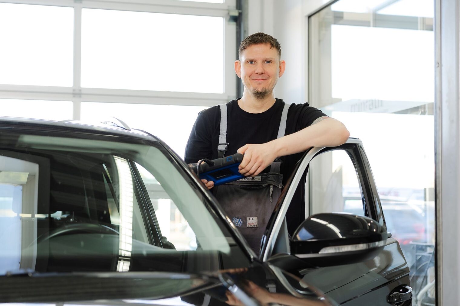 Thomas Kensik lehnt in der Werkstatt an einer geöffneten Autotür.