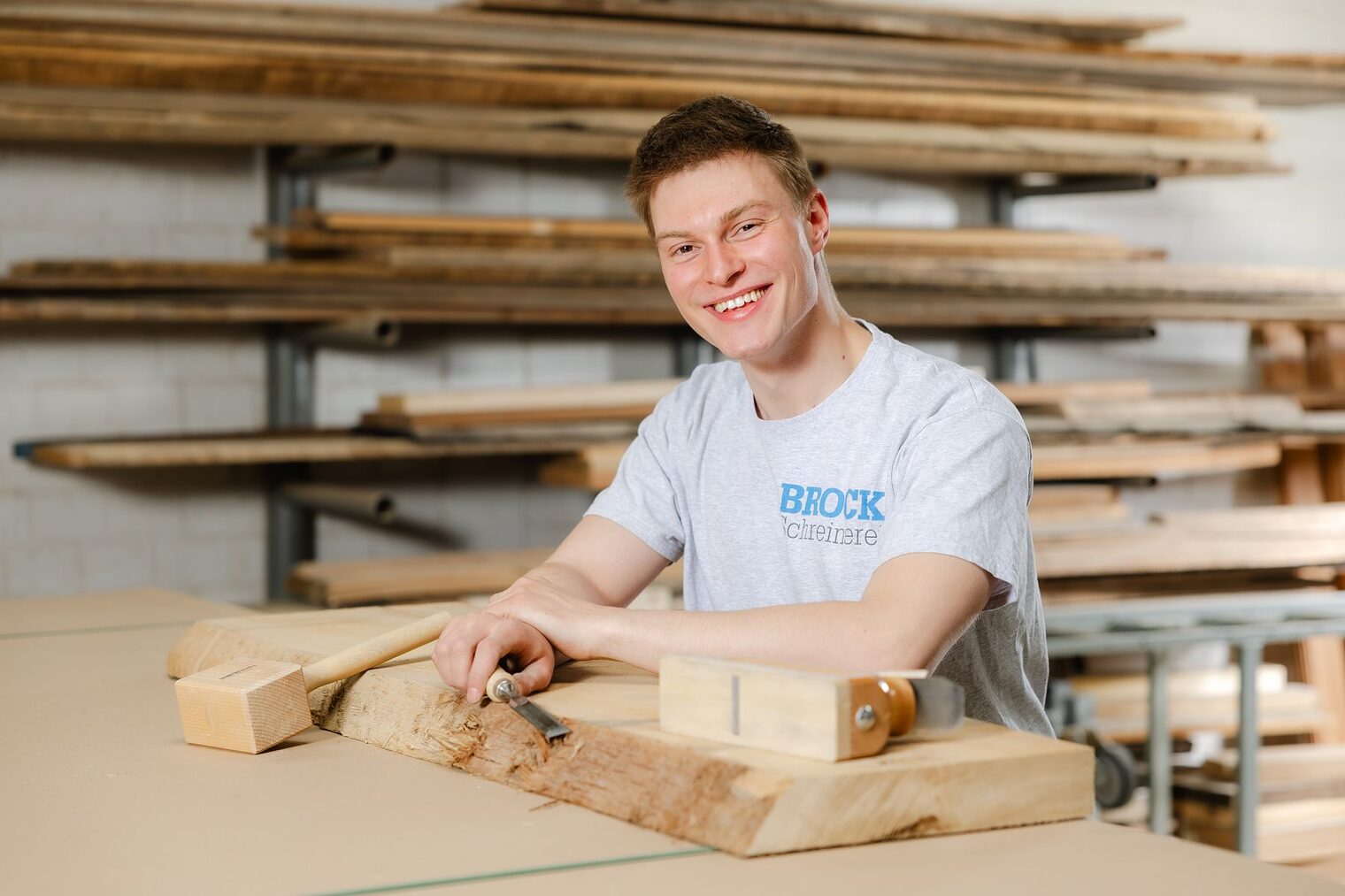 Luca Scheurer sitzt an einer Werkbank in einer Tischlerei