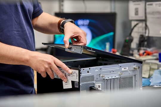Die Hände einer männlichen Person öffnen ein IT-Gerät.