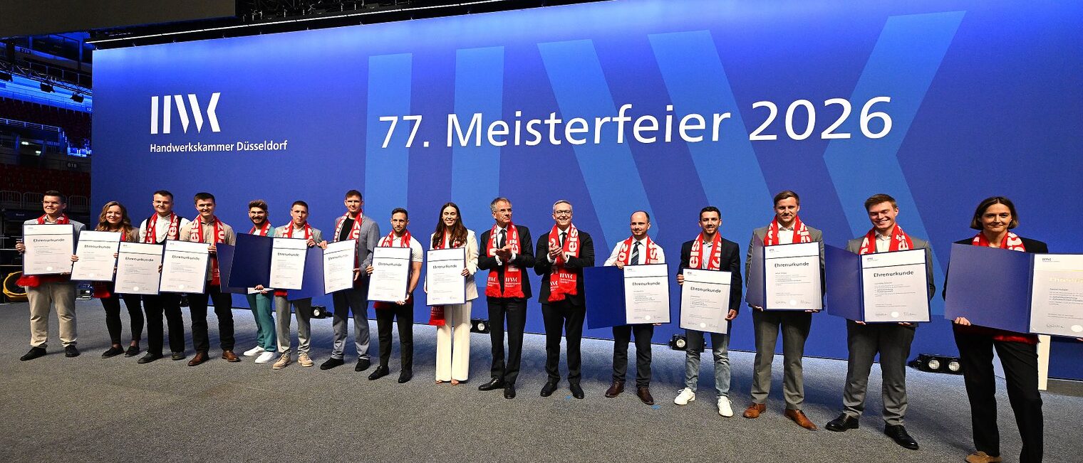 Auf der Meisterfeier-Bühne stehen 14 Jahresbestmeisterinnen und Jahresbestmeister und zeigen ihre Ehrenurkunden.