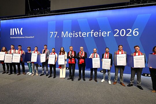 Auf der Meisterfeier-Bühne stehen 14 Jahresbestmeisterinnen und Jahresbestmeister und zeigen ihre Ehrenurkunden.