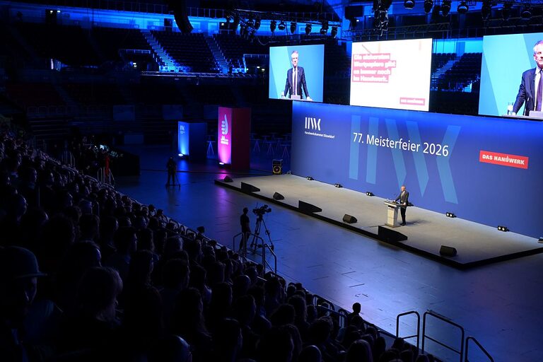 Kammerpräsident hält eine Rede auf der Bühne. Foto von der oberen Tribüne. Auf den beiden Monitoren über der Bühne das Live-Bild von Herrn Ehlert.