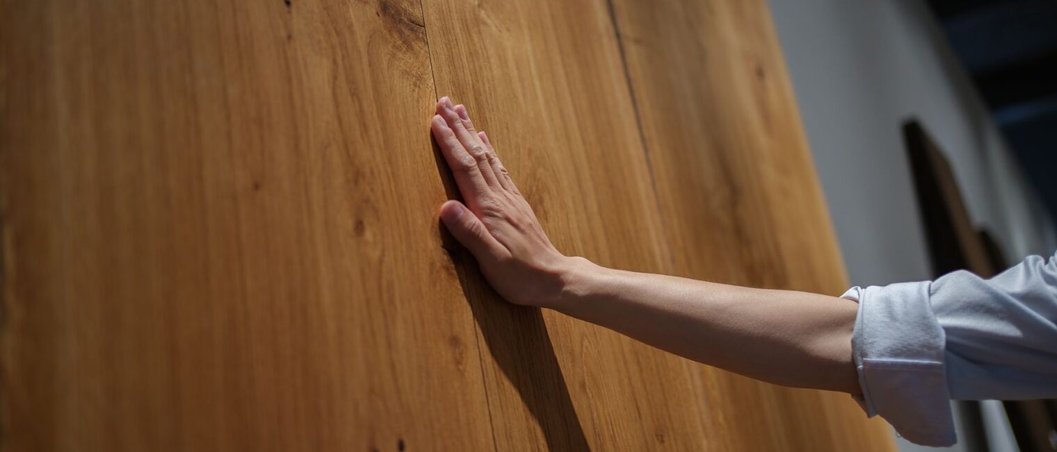 Eine Hand berührt eine stehende Holzplatte