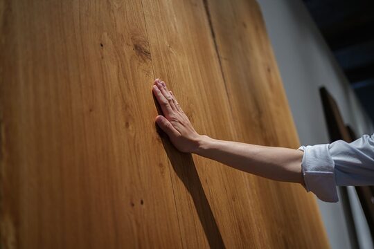 Eine Hand berührt eine stehende Holzplatte