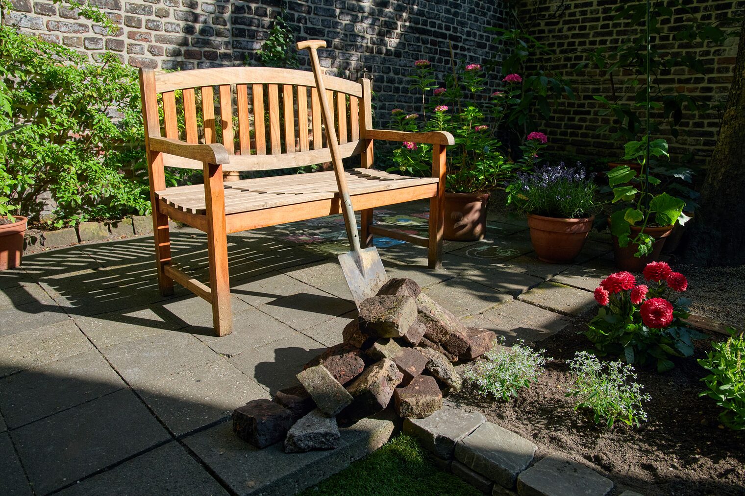 Garten mit Bank, Spaten und Blumen