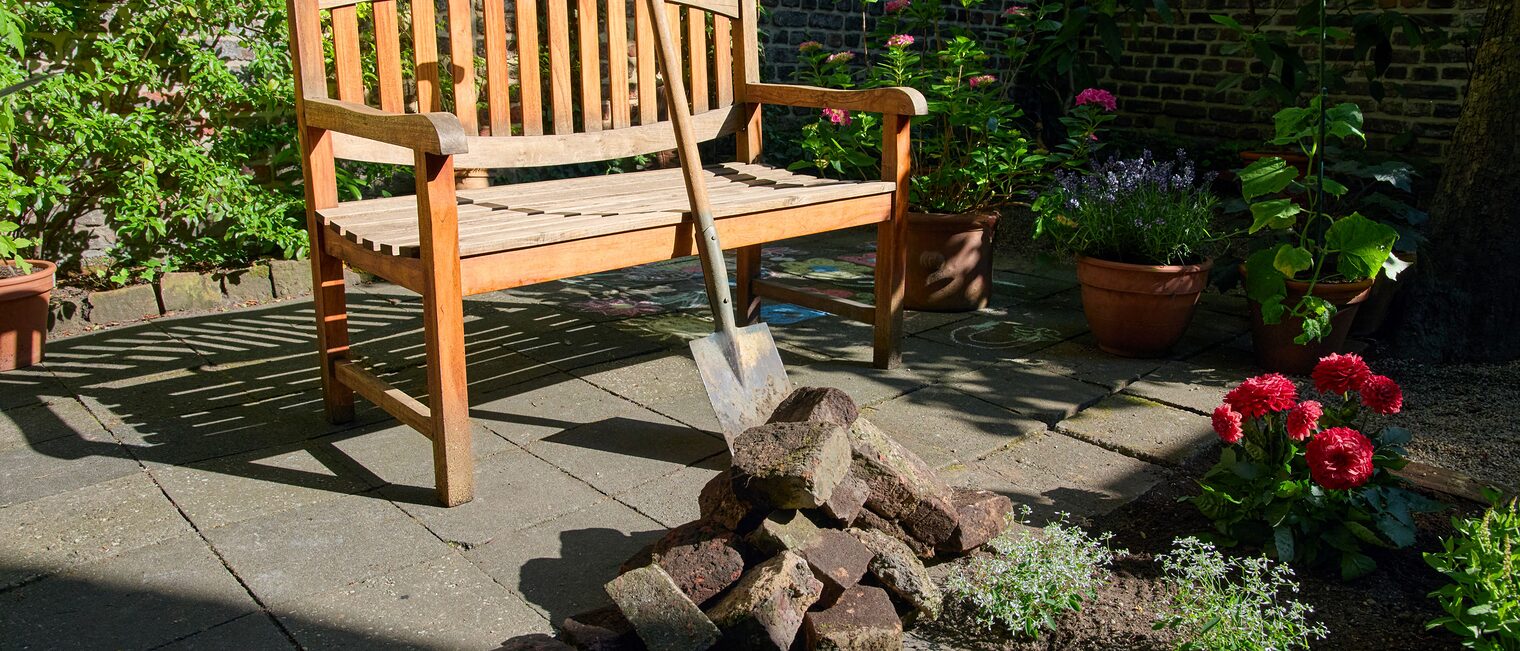 Garten mit Bank, Spaten und Blumen